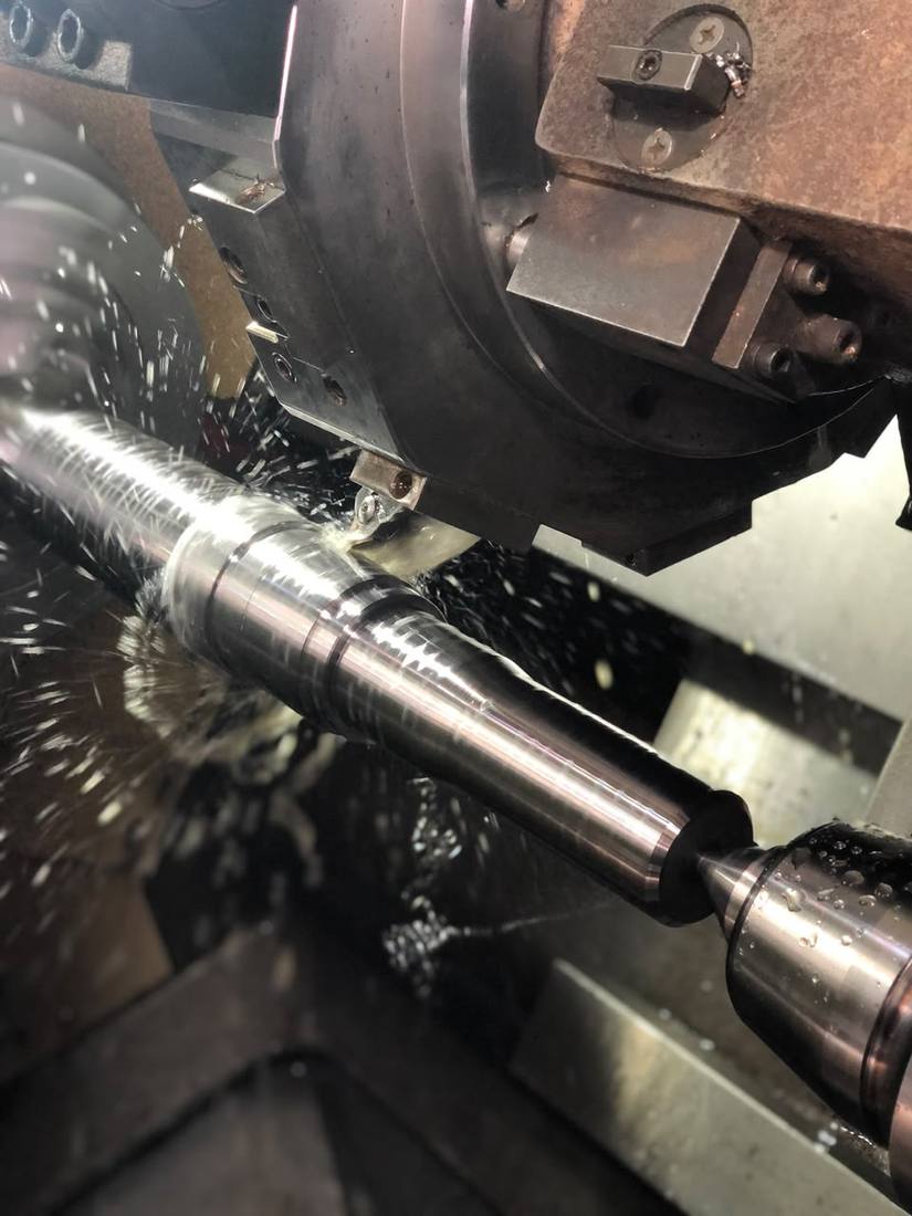Torneado CNC de un eje, viruta y refrigerante en pleno corte